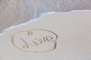 Honeymoon and romantic vacation concept. Word Love in a heart drawn on the beach near waves