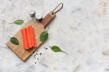 Wooden board with tasty crab sticks, spinach leaves and peppercorns on white background © Pixel-Shot