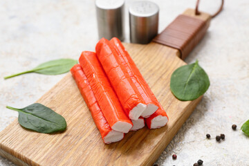 Wooden board with tasty crab sticks, spinach leaves and peppercorns on white background © Pixel-Shot