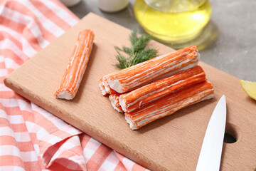 Wooden board with tasty crab sticks and dill on grey background © Pixel-Shot