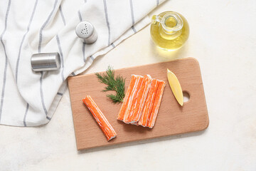 Wooden board with tasty crab sticks, dill and piece of lemon on white background © Pixel-Shot