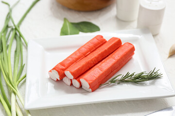 Plate with tasty crab sticks and green onion on white background © Pixel-Shot