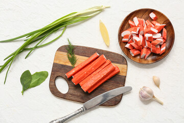 Wooden board and plate with tasty crab sticks on white background © Pixel-Shot