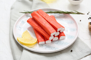 Plate with tasty crab sticks, slices of lemon and rosemary on white background © Pixel-Shot