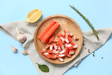 Wooden plate with tasty crab sticks and different spices on blue background © Pixel-Shot
