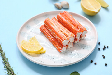 Plate with tasty crab sticks and different spices on blue background © Pixel-Shot