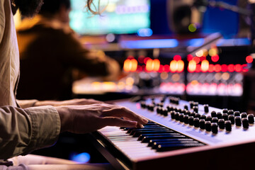 Male musician performing a hit song on electronic keyboard in recording studio, playing notes on midi controller to edit in post production. Artist singing in control room. Close up.