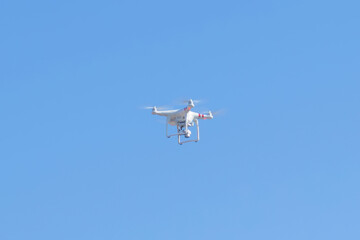 Drone flying high in a clear blue sky on a sunny day
