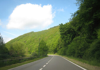 Winding road through lush green hills on a sunny day