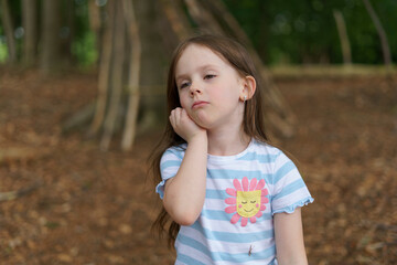 Little cute girl in a t-shirt in the summer in the forest. Concept of children's picnic in nature