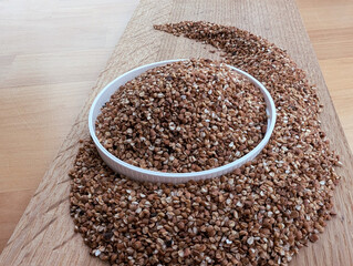 Raw buckwheat in a white bowl. Wooden cutting board