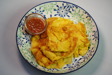 Fried omelet with shrimp paste chili dip in a small glass cup
