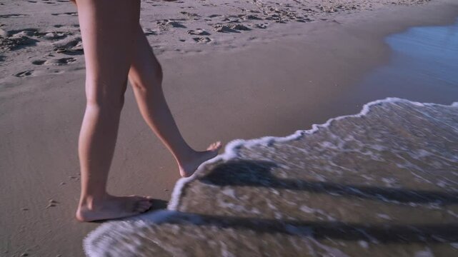 Piernas de chica joven paseando por la orilla del mar en la playa un d&iacute;a sensacional de vacaciones en verano.