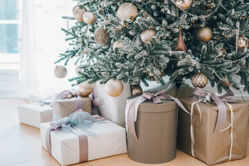 Decorated Christmas tree stands in sunlit living room, adorned with golden ornaments and twinkling lights. Wrapped presents, gift boxes under Christmas tree, festive atmosphere of winter holidays
