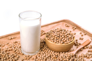 Glass of soy milk and soybeans in wooden bowl on white background.
