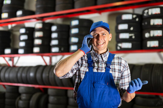 Auto mechanic talking on mobile phone with client in auto workshop