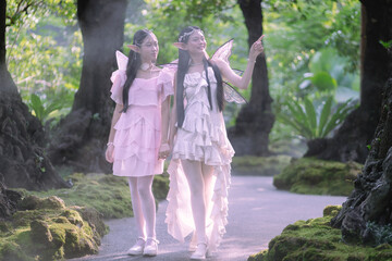 Portrait fantasy Angel Fairy Tale woman in forest natural trees. Elf girl fashion in pink dress with butterfly wings fairy tale story world. Walks in fresh green trees with magic radiance.