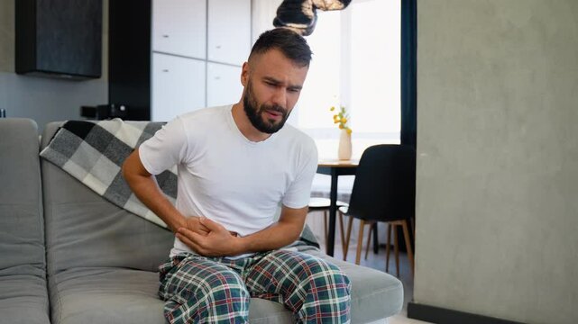 A Man Experiencing Severe Stomach Pain Sitting on Sofa