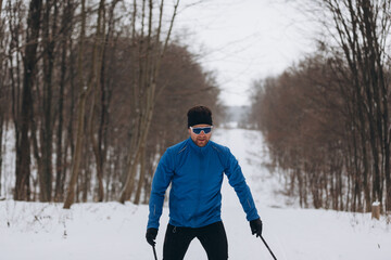 Cross-country skier advancing on a snowy forest trail
