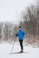 oung Caucasian male skier athlete skiing downhill on a cross-country trail in winter
