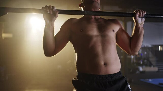 Close-up male athlete using talc powder, clapping getting ready to exercise, doing pull-ups in large gym