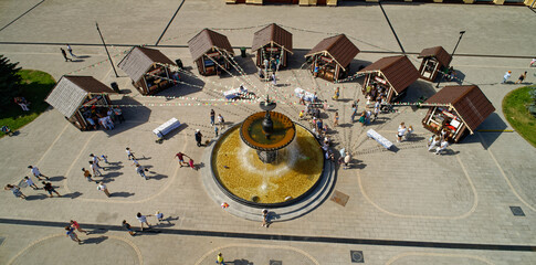 Group of people are gathered around a fountain in a plaza