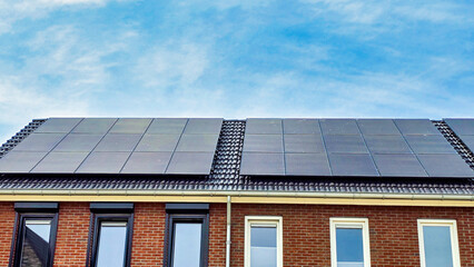 Fototapeta premium black solar panels on the roof against a sunny sky in the Netherlands, Close up of new building with black solar panels. Zonnepanelen, Zonne energie, Translation: Solar panel, Sun Energy