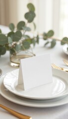 Blank wedding place card mockup on an elegant white plate with golden cutlery and eucalyptus
