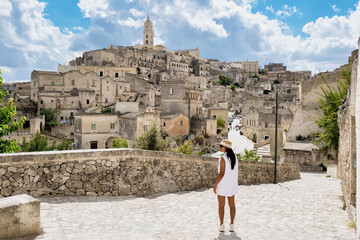 An Asian women traveler admires the stunning landscape of Matera, Puglia Italy, where ancient stone...