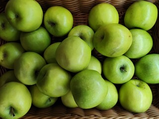 A basket filled with fresh, green Granny Smith apples.