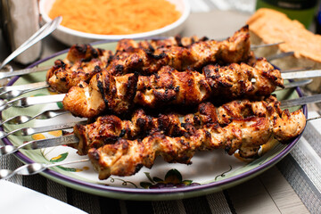grilled chicken kebab on whtie plate with metal skewers sticks