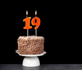 Birthday card with candle number 19 - Chocolate cake on black background.