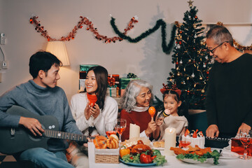 Multi-Generation Family Celebrate Christmas At Home Wearing Santa Hats And Antlers Opening Presents