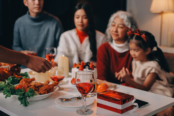Multi-Generation Family Celebrate Christmas At Home Wearing Santa Hats And Antlers Opening Presents