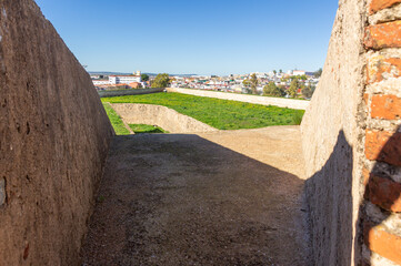 Cannon embrasure in a 17th-century fort, with a view of the moat and outer wall.