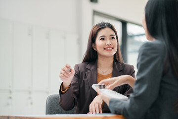 Two women in a business meeting, discussing ideas in a modern office environment, showcasing...