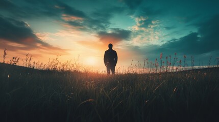 Silhouette of a man standing alone in a field at sunset