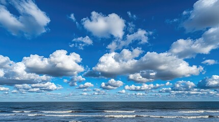 Endless ocean stretching under a vivid blue sky with fluffy clouds drifting across