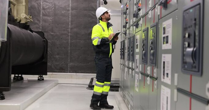 Electrical engineer with green uniform checking and inspecting at MDB panel or Main Distribution Boards of factory