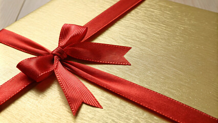 Golden gift box with red ribbon, perfect for celebrations and holidays