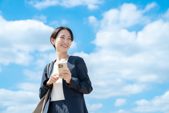ビジネス女性・青空・スマートフォン