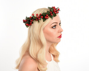 close up portrait of beautiful blonde female model wearing holly and ivy Christmas  fantasy wreath crown headdress. isolated silhouette, looking away in side profile on white studio background.