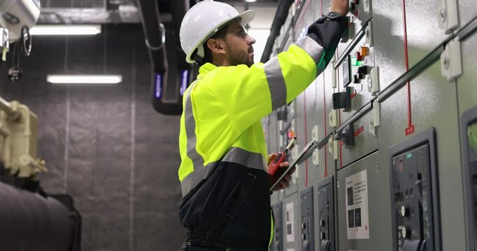Electrical engineer with green uniform checking and inspecting at MDB panel or Main Distribution Boards of factory