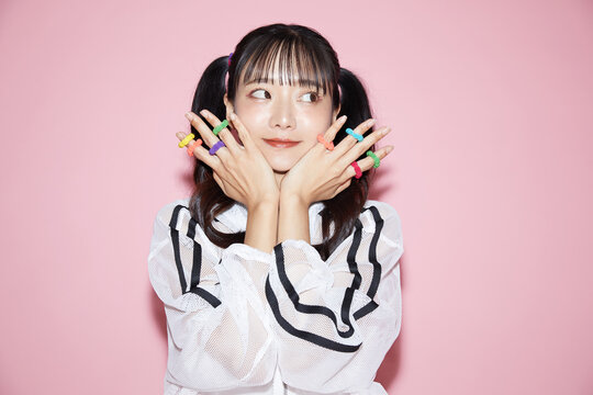 ピンク背景で撮影をしたスポーティな服装をした若い女性のキュートなポートレート