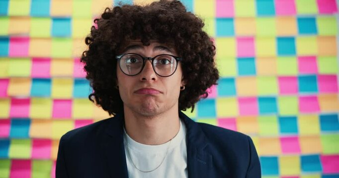 Clueless, man and glasses with shrug for confusion, unsure or puzzle expression on a colorful background. Male person, doubtful or confused model with no clue or uncertain face for question or doubt