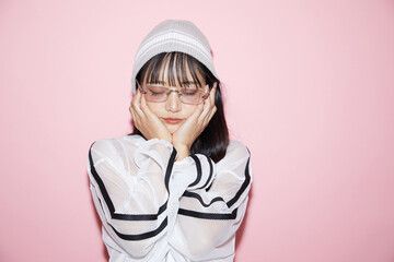 ピンク背景で撮影をしたスポーティな服装をした若い女性のキュートなポートレート