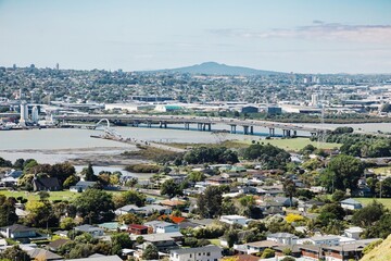Naklejka premium MANGERE, AUCKLAND, AUCKLAND, NEW ZEALAND, High-angle view of a bustling city, showcasing residential areas in Onehunga, industrial zones, and a highway bridge spanning a river. 