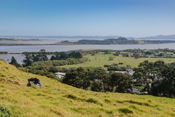 MANGERE MOUNTAIN, AUCKLAND, AUCKLAND, NEW ZEALAND, Panoramic view of a rural landscape out to puketutu island in the Manukau Harbour. Pastures, a waterway, and residential areas are visible. 