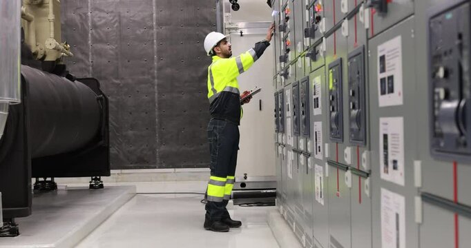 Electrical engineer with green uniform checking and inspecting at MDB panel or Main Distribution Boards of factory