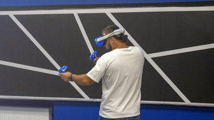 A man is playing a video game with a VR headset on. He is holding a controller in each hand © Антон Скрипачев